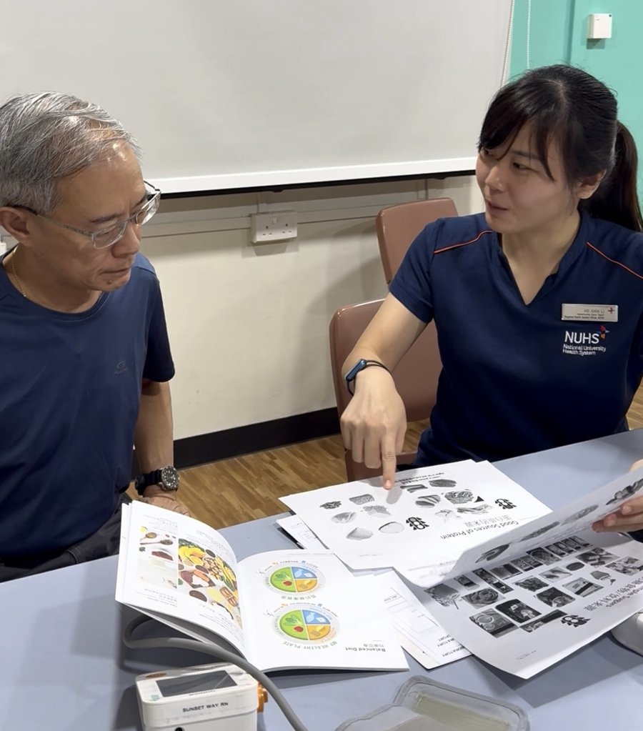 Community Health Coach Ms Ho going through dietary materials with Mr Seeto